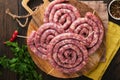 Raw spiral pork sausages. Fresh pork sausages tasty twisted spiral for bbq on white stand with spices and herbs for Octoberfest pa Royalty Free Stock Photo