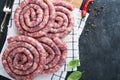 Raw spiral pork sausages. Fresh pork sausages tasty twisted spiral for bbq on white stand with spices and herbs for Octoberfest pa Royalty Free Stock Photo