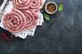Raw spiral pork sausages. Fresh pork sausages tasty twisted spiral for bbq on white stand with spices and herbs for Octoberfest pa Royalty Free Stock Photo
