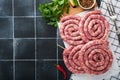 Raw spiral pork sausages. Fresh pork sausages tasty twisted spiral for bbq on white stand with spices and herbs for Octoberfest pa Royalty Free Stock Photo