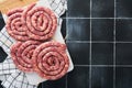 Raw spiral pork sausages. Fresh pork sausages tasty twisted spiral for bbq on white stand with spices and herbs for Octoberfest pa Royalty Free Stock Photo