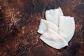Raw Squid or Calamari tubes on a kitchen table. Dark background. Top view. Copy space