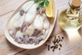 Raw squid fillet on a plate over wooden table. Small calamary tubes, olive oil and lemon prepared for cooking. Fresh squid Royalty Free Stock Photo