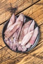 Raw squid, fresh calamari in a plate. Wooden background. Top view