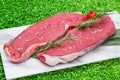 Raw steak meat on white dish with green grass background Royalty Free Stock Photo