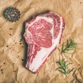 Raw steak rib-eye with seasoning on craft paper, square crop Royalty Free Stock Photo