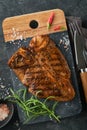 Raw steak t-bone or porterhouse. Steak t-bone or porterhouse in sauce with spices, salt and rosemary on a black ceramic plate on c Royalty Free Stock Photo