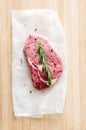 Raw steak on wooden surface with salt and pepper