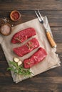 Raw steaks. Top blade steaks on wood burning board with spices, rosemary, vegetables and ingredients for cooking on old wooden bac