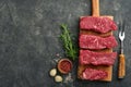 Raw steaks. Top blade steaks on wood burning board with spices, rosemary, vegetables and ingredients for cooking on black backgrou