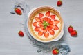 Raw strawberry tart on the gray kitchen background. Berries cheesecake decorated with organic fresh strawberries and mint