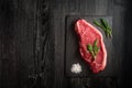 raw strip loin steak on black wooden background