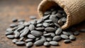 Raw sunflower seeds with gray stripes spilling from burlap sack on rustic surface Royalty Free Stock Photo
