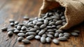 Raw sunflower seeds with gray stripes spilling from burlap sack on rustic surface Royalty Free Stock Photo