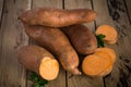 Raw sweet potatoes on rustic wooden background. Royalty Free Stock Photo