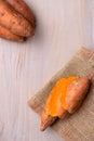 Raw sweet potatoes on wooden background in burlap sack Royalty Free Stock Photo