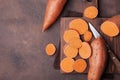 Raw sweet potatoes on wooden kitchen board top view. Organic food. Royalty Free Stock Photo