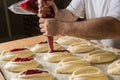 Raw sweet yeast dough on a baking sheet, filling buns jam. Preparation for baking. The concept of chefs and baking. Royalty Free Stock Photo