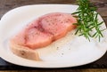 Raw Swordfish fillet covered with black pepper and with rosemary sprigs on white plate