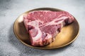 Raw T-bone porterhouse beef meat Steak on golden metalic plate. Gray background. Top view