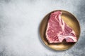 Raw T-bone porterhouse beef meat Steak on golden metalic plate. Gray background. Top view. Copy space