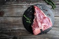 Raw T-bone Steak or porterhouse steak for grill or BBQ with spices and herbs on slate board and woden rustic background, top view Royalty Free Stock Photo