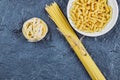 Raw tagliatelle, spaghetti and fusilli on blue background