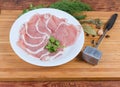 Raw tenderized boneless pork chops, spices, tenderizer on cutting board