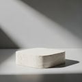 Minimalist concrete block casting dramatic shadow on smooth white surface in natural light setting Royalty Free Stock Photo