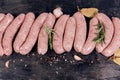 Top view raw pork sausages among spices on dark surface Royalty Free Stock Photo