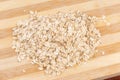 Raw thick-rolled oats on wooden cutting board close-up