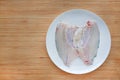 Raw tilapia fish fillet on white plate against wooden board background with copy space Royalty Free Stock Photo