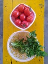 Raw tomatoes and coriander in the baskets placed on a wooden table