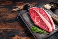 Raw top sirloin cap beef meat steaks on butcher board with meat cleaver. Dark woden background. Top view. Copy space Royalty Free Stock Photo