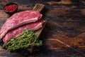 Raw top sirloin cap steak or Picanha steak on wooden board with thyme. Dark wooden background. Top view. Copy space Royalty Free Stock Photo