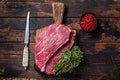 Raw top sirloin cap steak or Picanha steak on wooden board with thyme. Dark wooden background. Top view