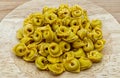Raw Tortellini in a wooden bowl on wooden table. Traditional italian pasta. Royalty Free Stock Photo