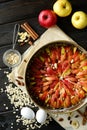 Raw traditional homemade german apple pie cake with nuts and cinnamon in form for baking on dark wooden table