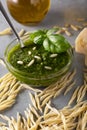 Raw trofie pasta and a glass bowl with pesto souace