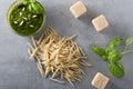 Raw trofie pasta and a glass bowl with pesto souace