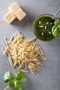 Raw trofie pasta and a glass bowl with pesto souace