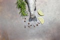 Raw trout fish tails with rosemary sprigs, lemon wedges and pepper