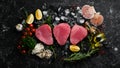 Raw tuna steak with spices on ice. On a dark background. Royalty Free Stock Photo