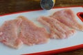 Raw turkey fillet breast sliced on an white cutting board