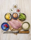 Raw turkey on paper with knife lemon meat onion peas salt pepper on wooden rustic background top view