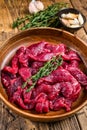 Raw uncooked beef meat sliced in strips with fresh herbs for beef stroganoff. wooden background. Top view Royalty Free Stock Photo