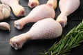 Raw uncooked chicken legs, drumsticks , with seasoning and herbs rosemary and thyme, on black wooden table background Royalty Free Stock Photo