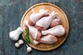 Raw uncooked chicken legs, drumsticks on wooden board, meat with ingredients for cooking