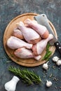 Raw uncooked chicken legs, drumsticks on wooden board, meat with ingredients for cooking Royalty Free Stock Photo