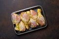 Raw uncooked chicken legs in green marinade with seasonings in black plastic container top view on dark rustic Royalty Free Stock Photo